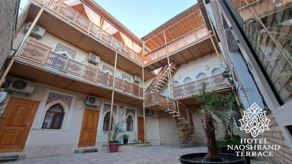 a building with stairs and a tree in the courtyard at Hotel Naqsh-band Terrace in Bukhara