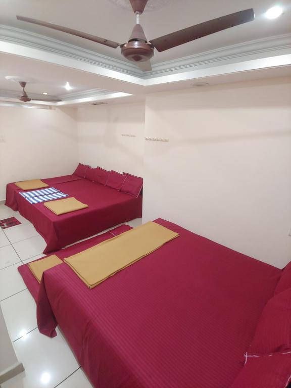 2 bedden in een witte kamer met rode lakens bij Ambai Guest House in Kolhapur