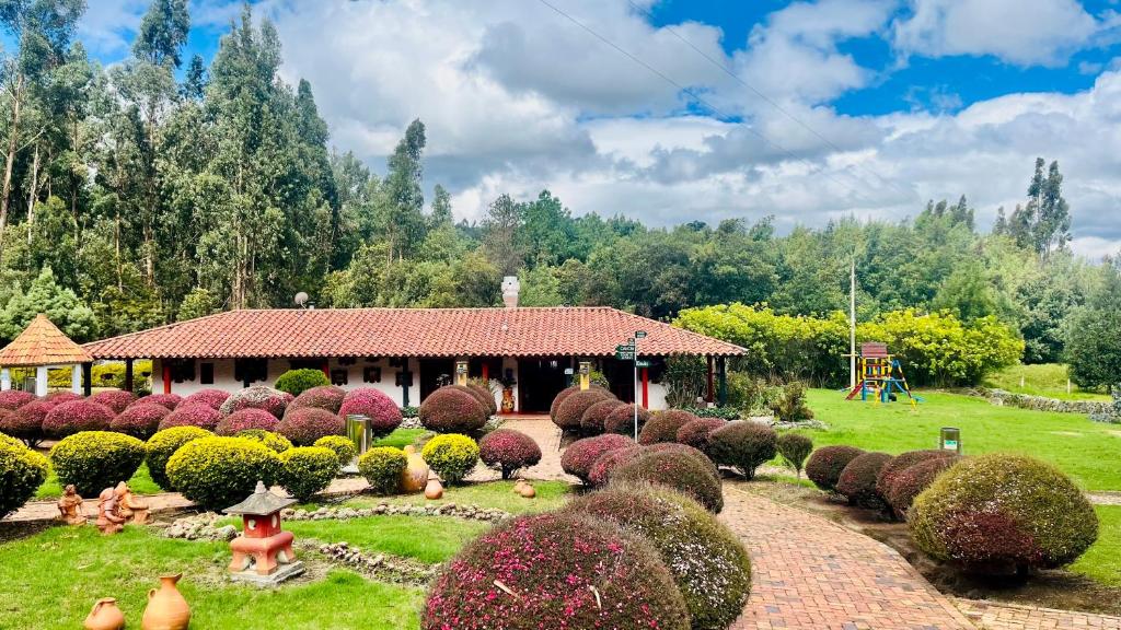 a garden with a pavilion in the background with bushes at Posada de Aquilino MC in Cucunubá