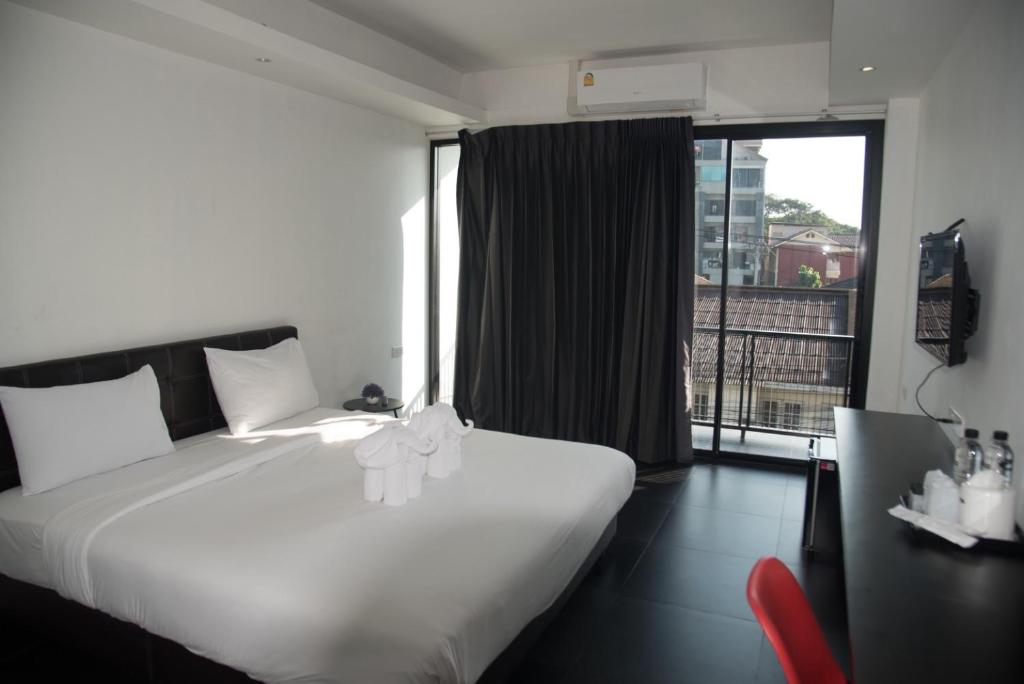 A modern guest room with a double bed, balcony access, desk and air conditioner.