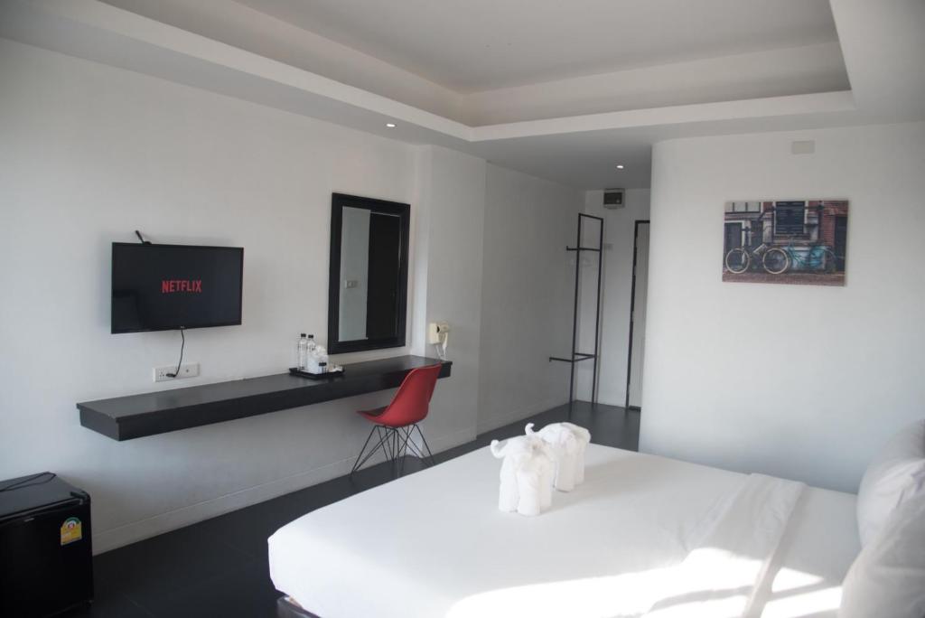 A guest room with a double bed, wall-mounted Netflix television, vanity desk and open storage.