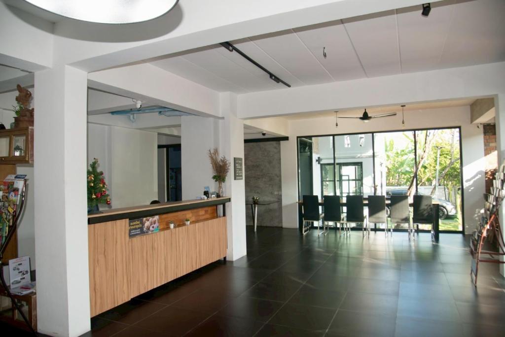 An open hotel lobby with a reception counter, dining tables and large windows.