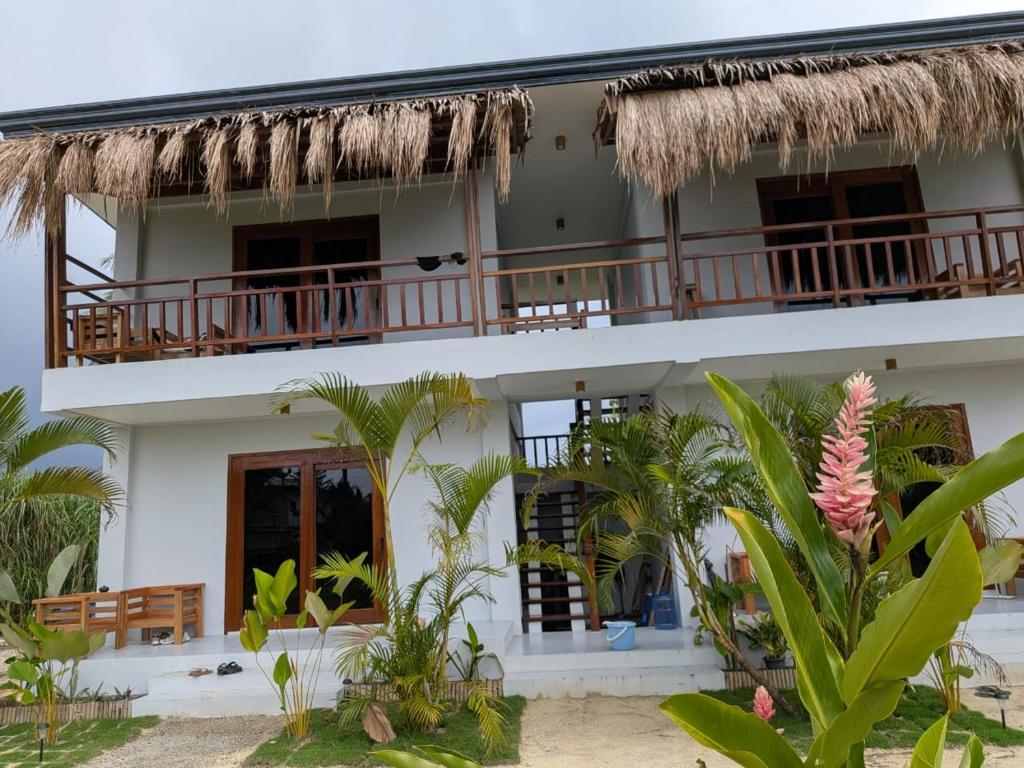 a white building with a balcony and palm trees at Cozy Shell in General Luna