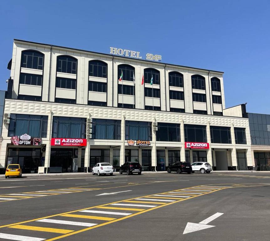 een groot wit gebouw met auto's ervoor geparkeerd bij Pandora Hotel in Muruntau