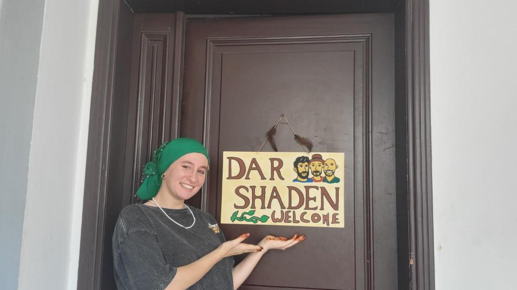 a woman standing in front of a door with a sign at Dar Shaden hostel in Muscat