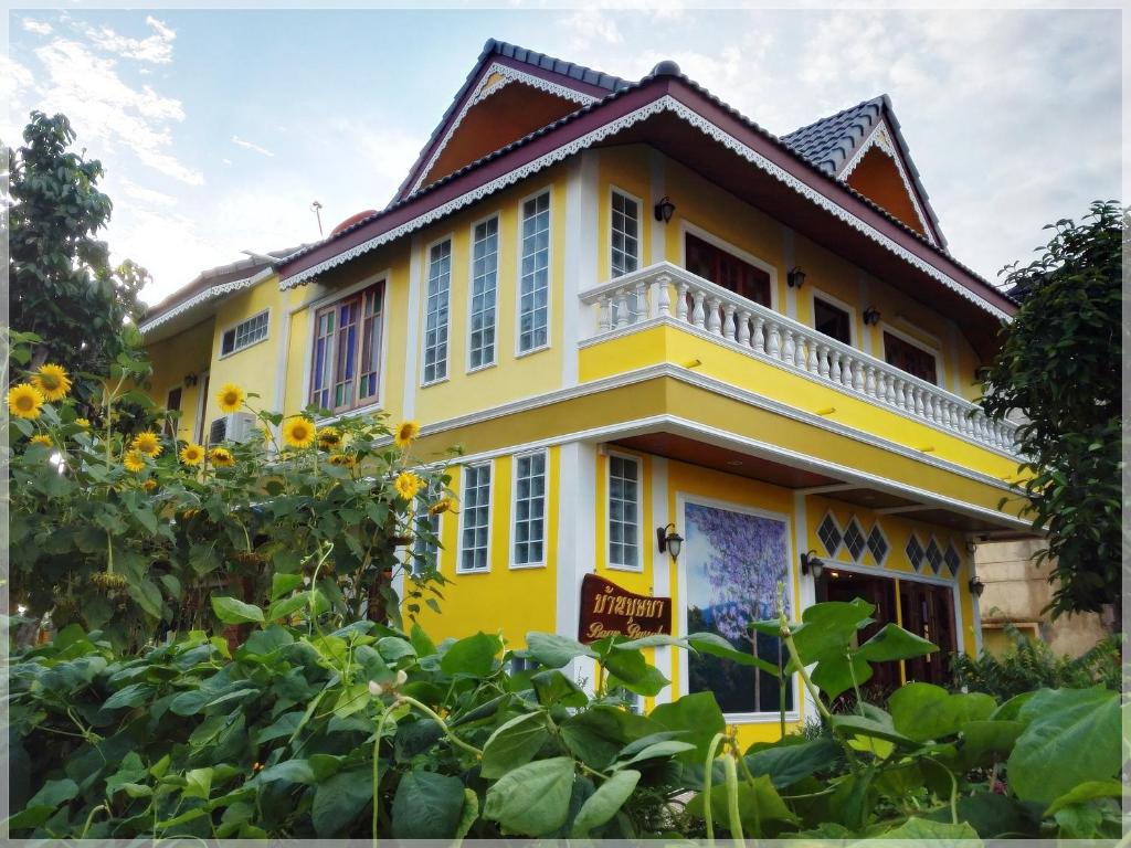 uma casa amarela com girassóis à frente em Baan Bussaba Hotel em Trang