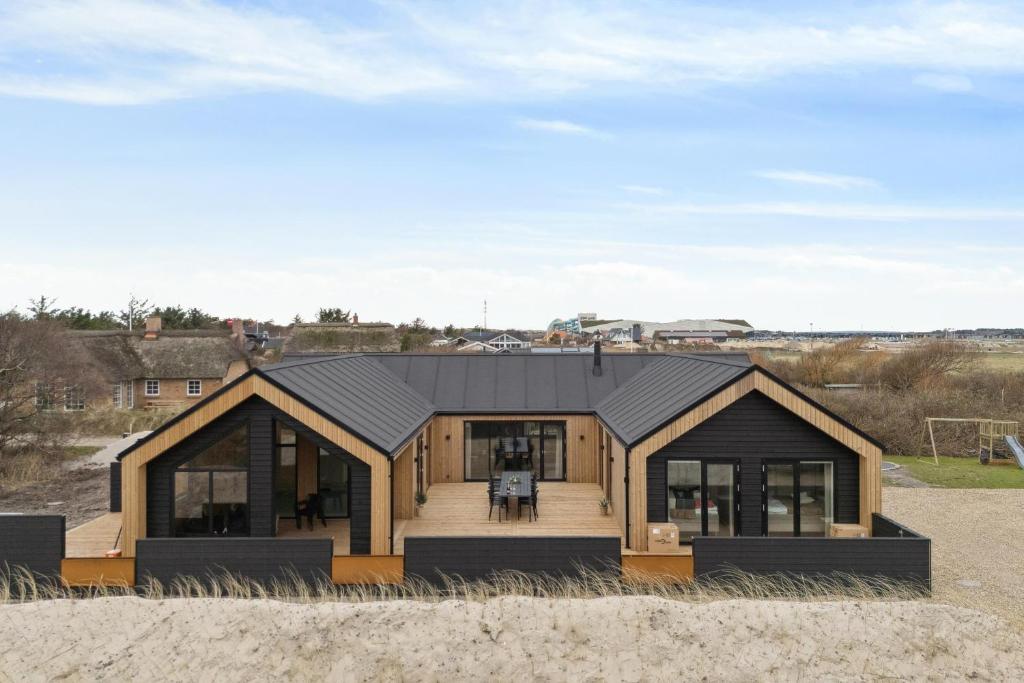a house with a black roof on the beach at Feriehus 1147 in Ringkøbing