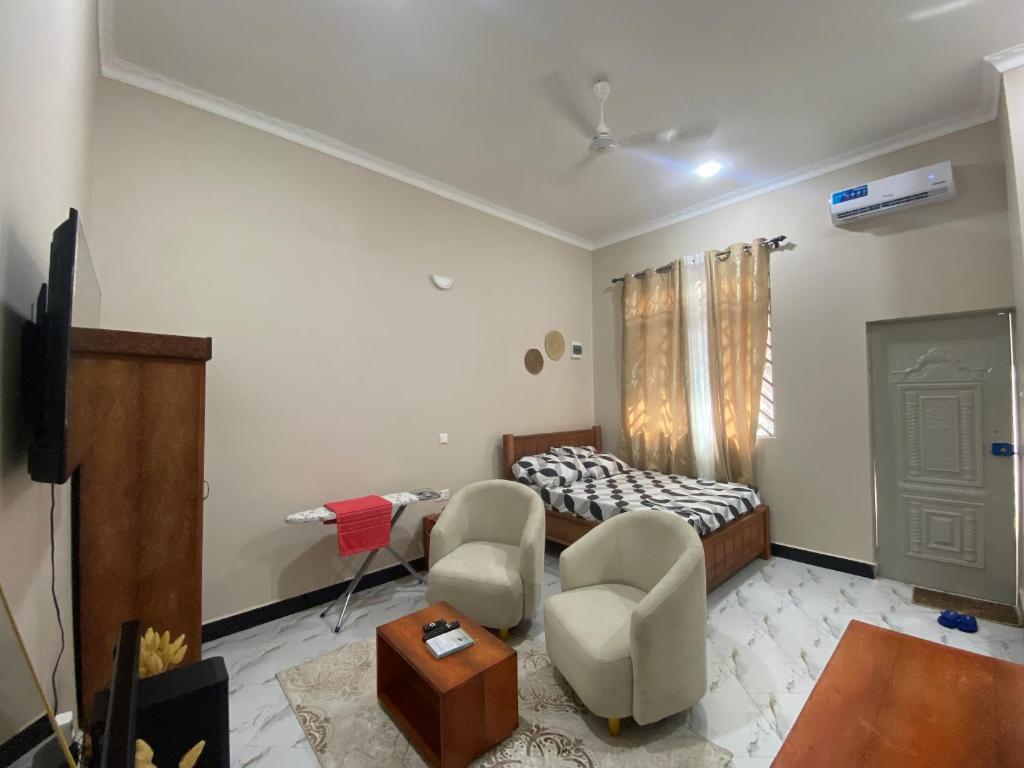 a living room with a bed and two chairs at Mnazinisky B&B in Zanzibar City