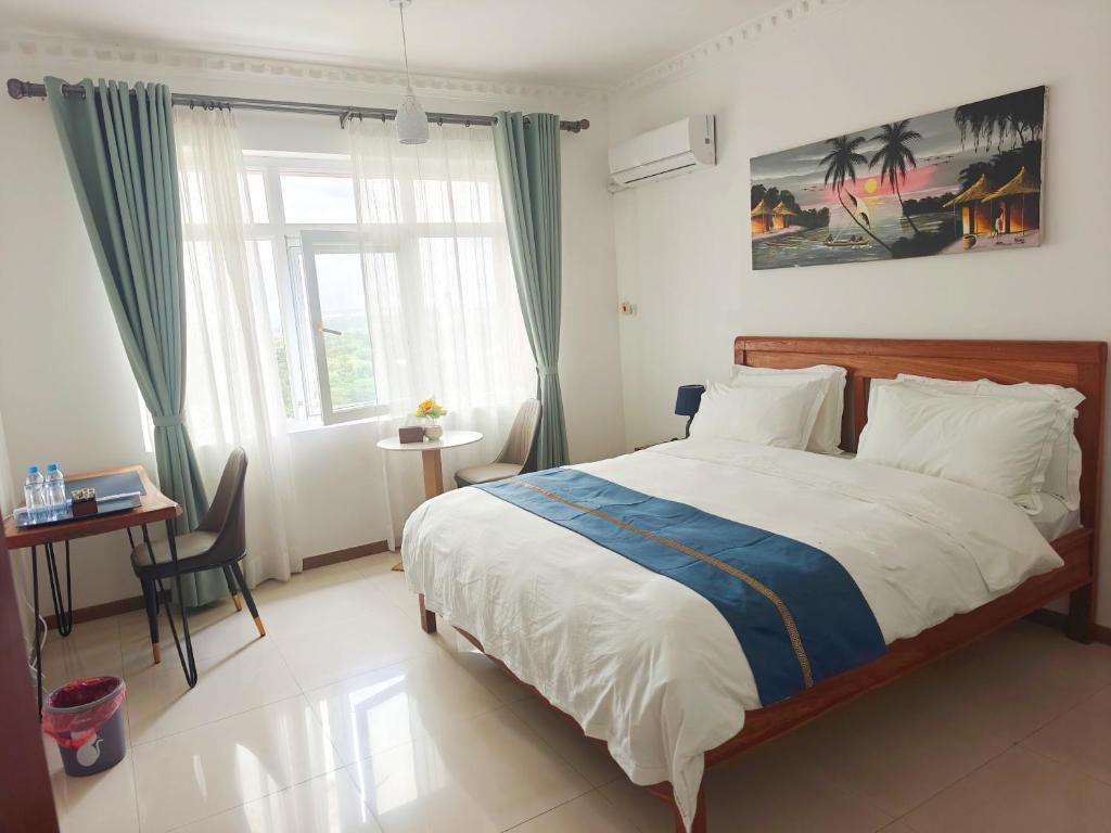 a bedroom with a bed and a desk and a window at Zawadi Apartment in Dar es Salaam