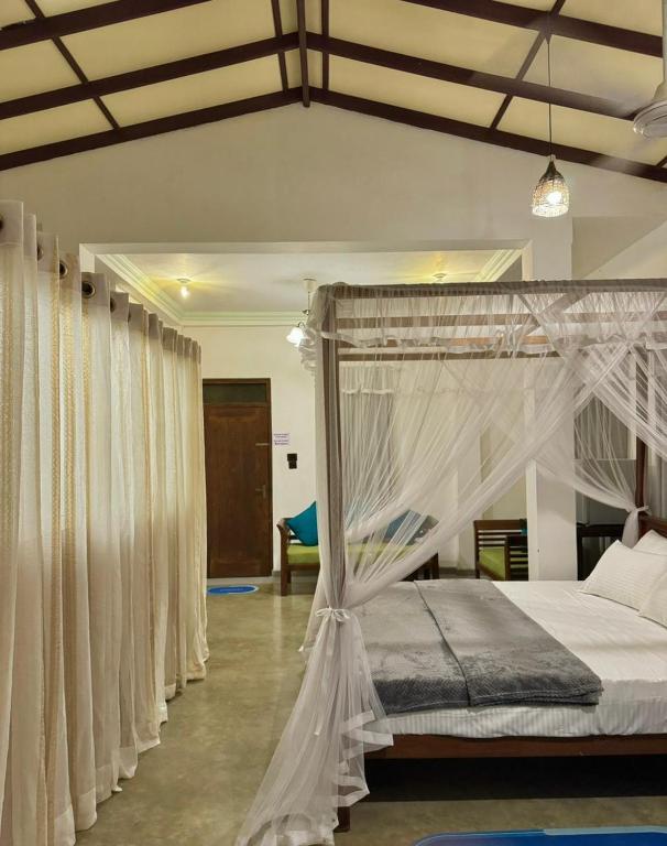 a bedroom with a canopy bed with white curtains at Villa SeaLoom in Galle