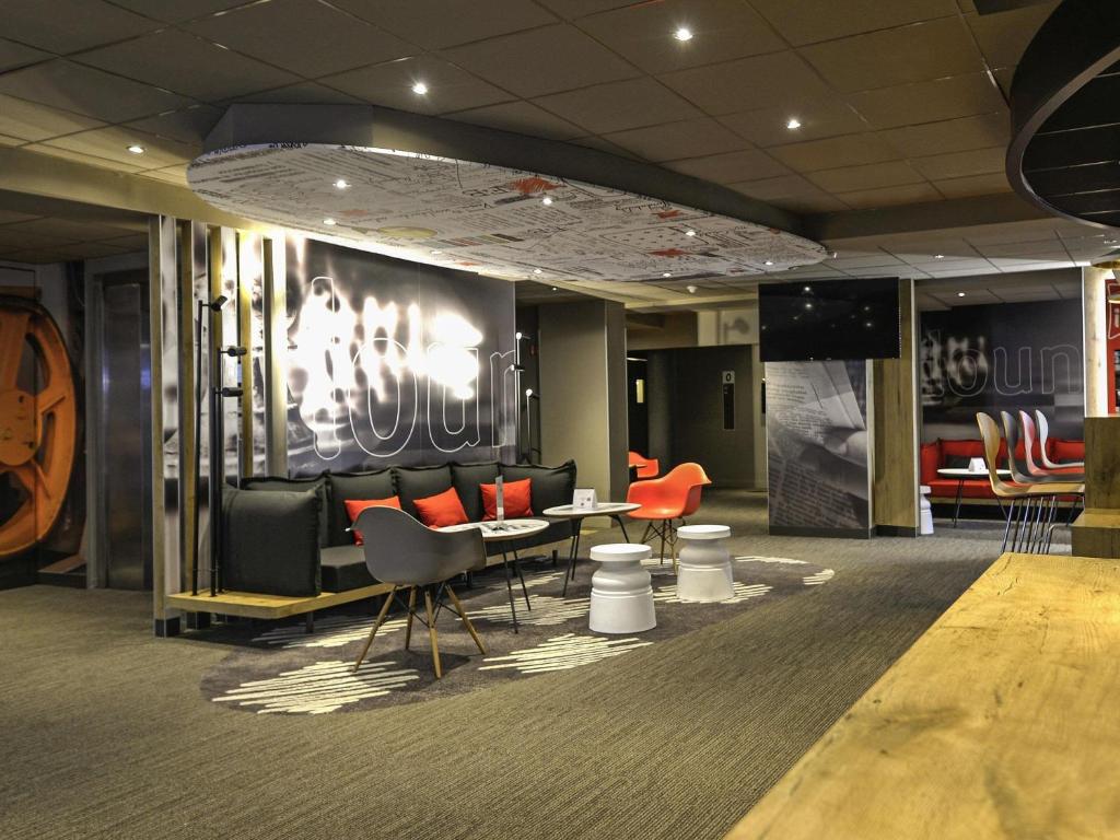 een lobby met banken en een tafel en stoelen bij ibis Château de Fontainebleau in Fontainebleau
