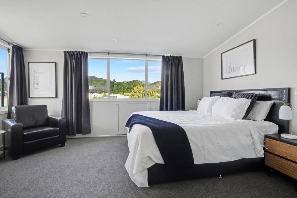 een slaapkamer met een bed, een stoel en een raam bij The Upper Rooms in Nelson