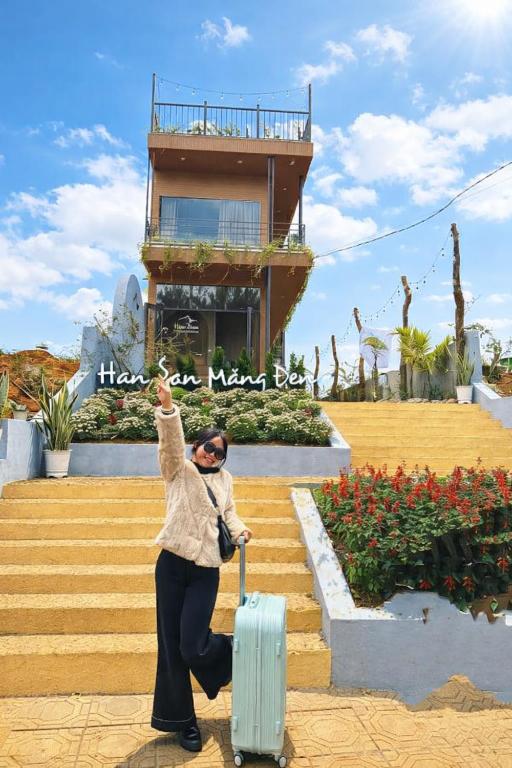 a woman is standing on the stairs with a suitcase at Han San Homestay Măng Đen in Kon Plong