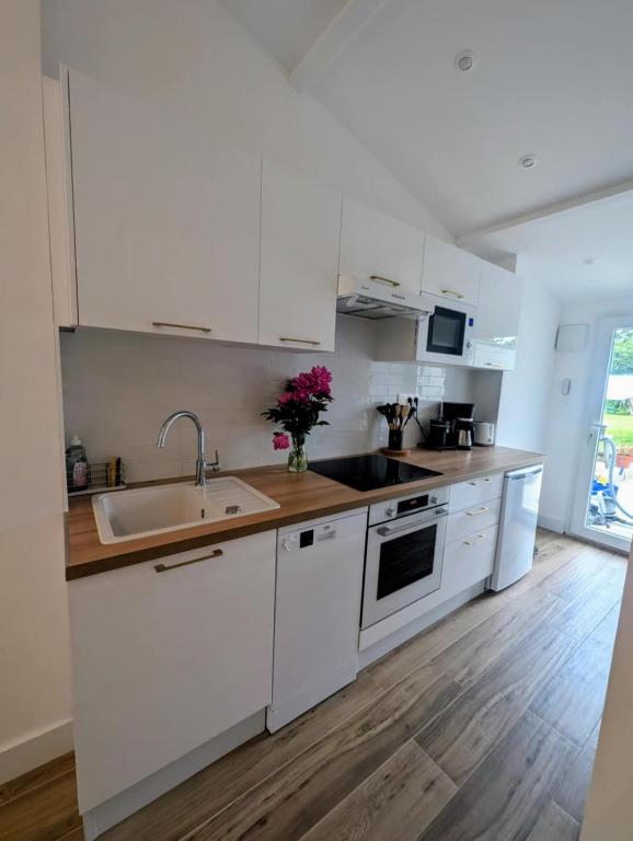 a kitchen with white cabinets and a sink at Studio RDC proche aéroport in Saint-Laurent-de-Mure