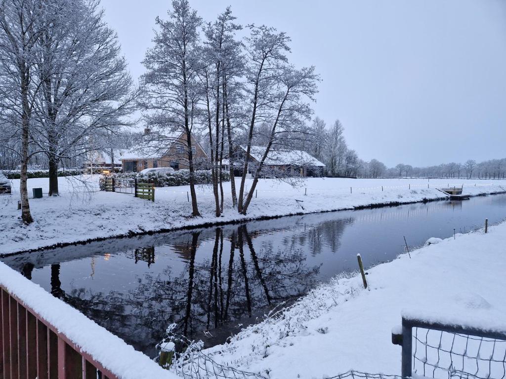 een rivier bedekt met sneeuw naast een hek bij Grutsk op 12 in Drachten