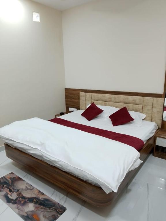 a bedroom with a bed with white sheets and red pillows at Hotel Sobhagyam in Kekri