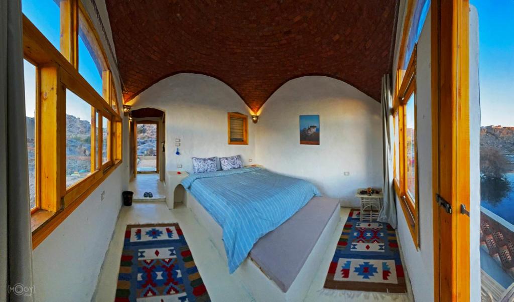 a bedroom with a bed in a room with windows at ASSINGAR Island in Aswan