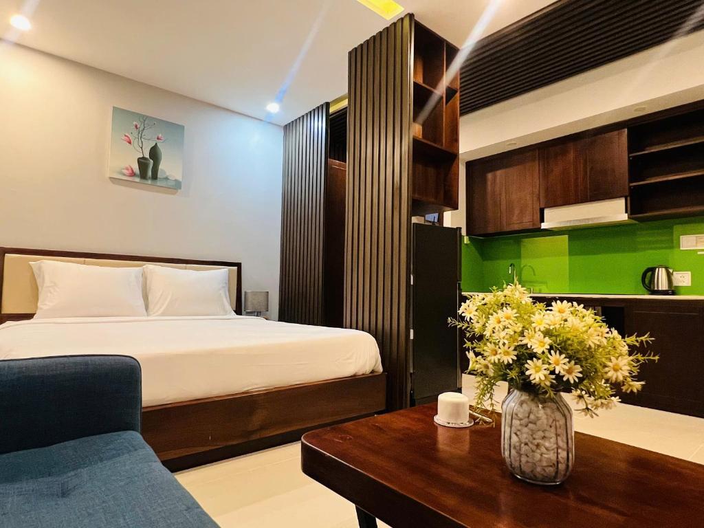 An open-plan room with a bed, blue sofa, coffee table and green-backed kitchenette.