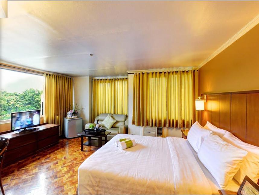 Habitación de hotel con cama grande y TV en The Corporate Inn Hotel, en Manila