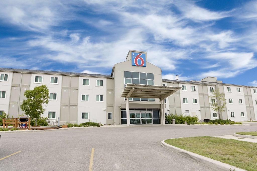 a large white building with a sign on top of it at Motel 6-Brandon, MB in Brandon