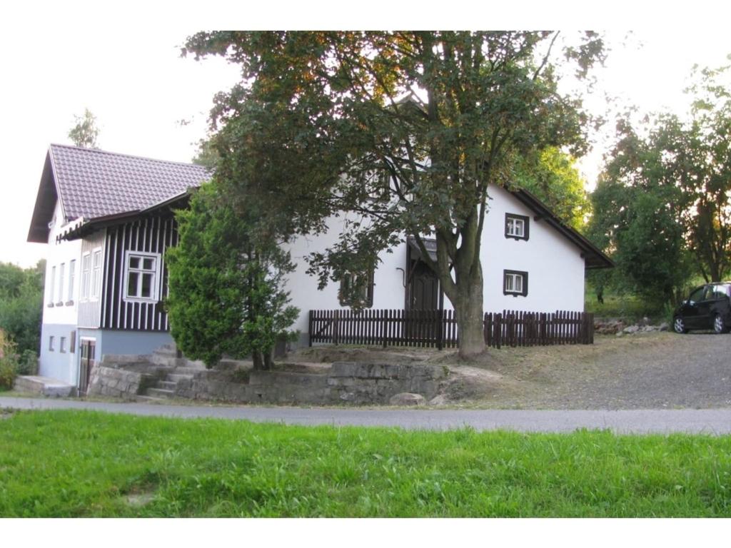 a white house with a tree in front of it at Holiday home in a quiet, authentic mountain village with a view of the surrounding hills in Zlatá Olešnice
