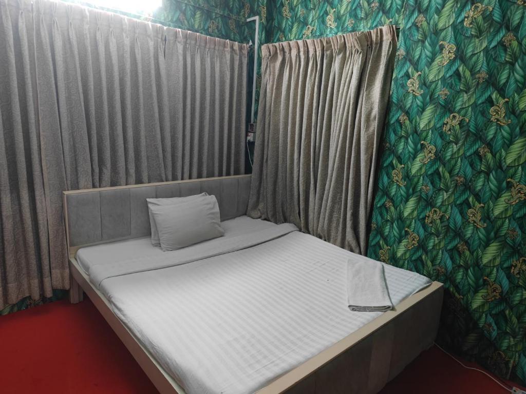 een klein bed in een kamer met een gordijn bij Hotel Golden Bird in Dhaka