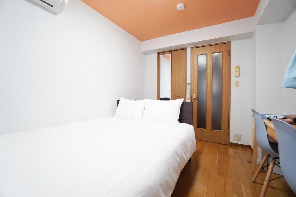 a bedroom with a large white bed and a desk at Mary's Room Hakata in Sumiyoshi