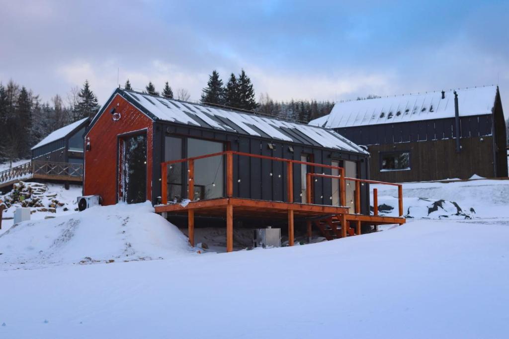 een rood en zwart gebouw in de sneeuw bij Domek Jak z Obrazka in Sierpnica