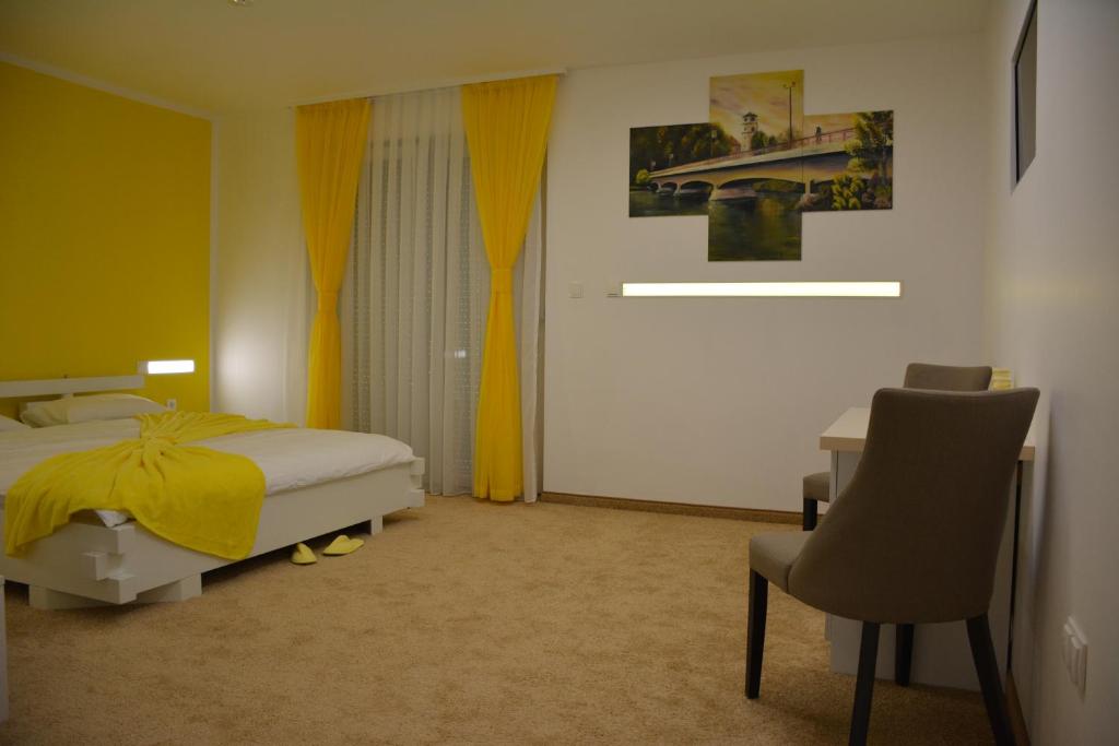 a bedroom with a bed and a desk and a chair at Hotel Vrata Bosne in Velika Kladuša