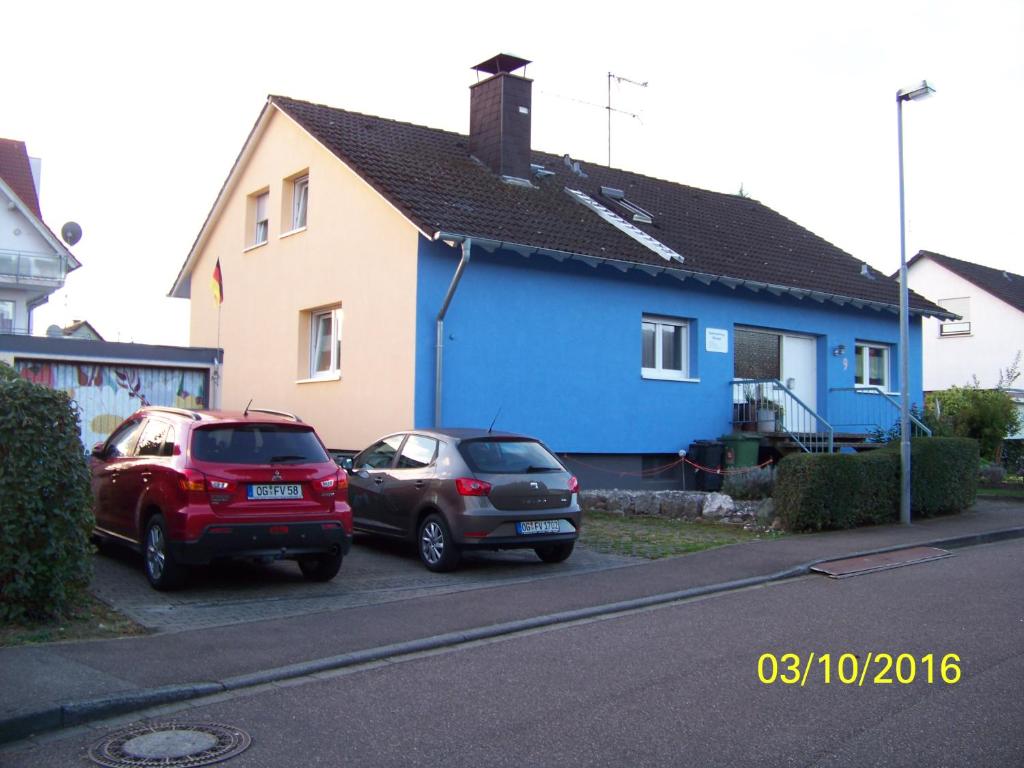 dos autos estacionados frente a una casa azul en Ferienwohnung Villringer, en Orschweier