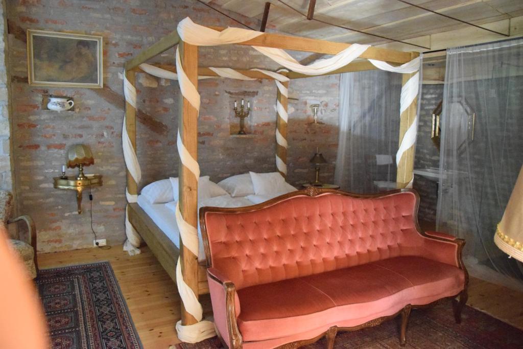 a bedroom with a four poster bed with a red couch at Luca Háza Panzió in Feketeerdő