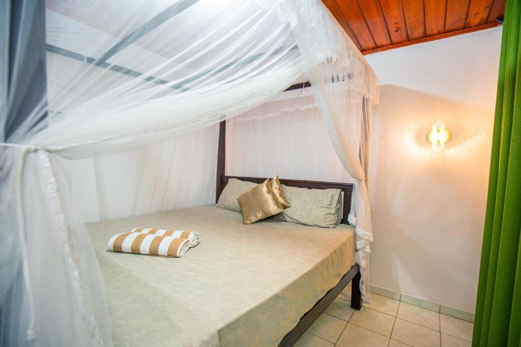 a bed in a room with a canopy at Rithu villa in Hikkaduwa