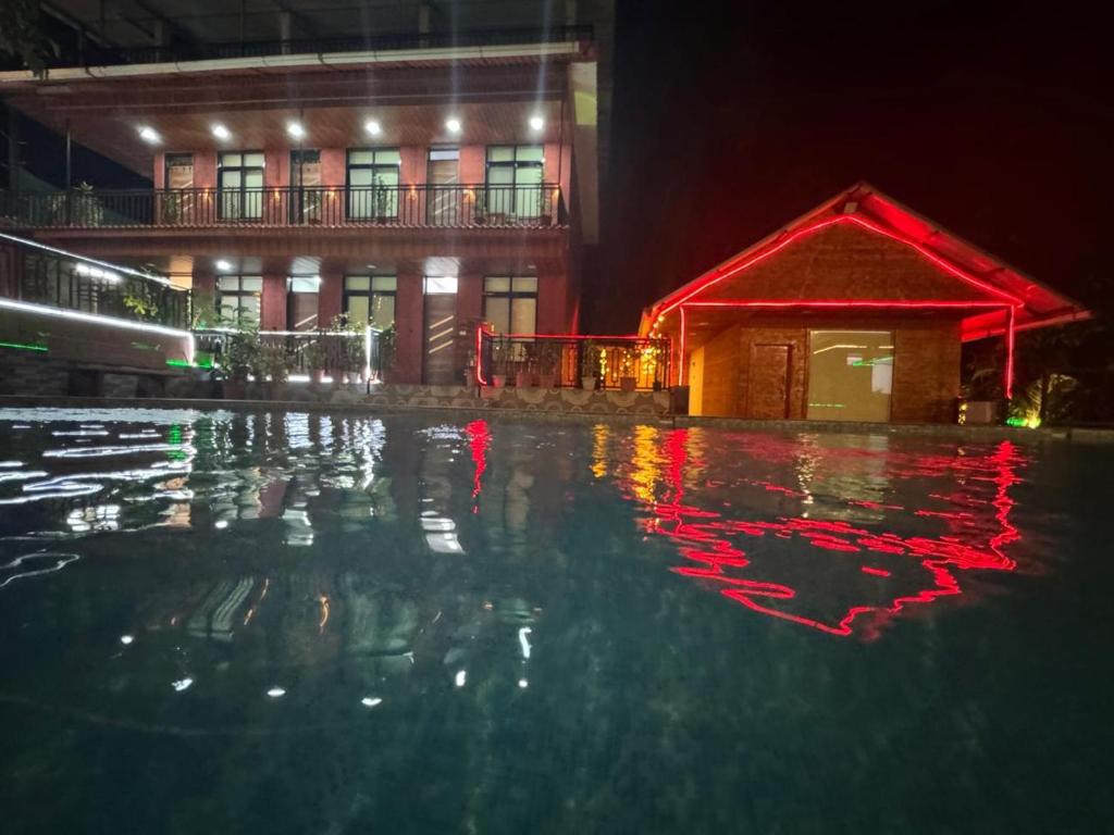 a pool of water in front of a building at night at Greenwood Resort in Dhamni