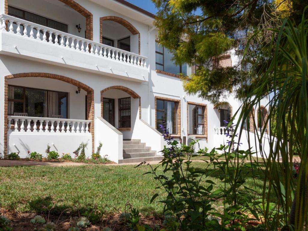 a large white house with a green yard at 5 Rembrandt Guesthouse in Somerset West