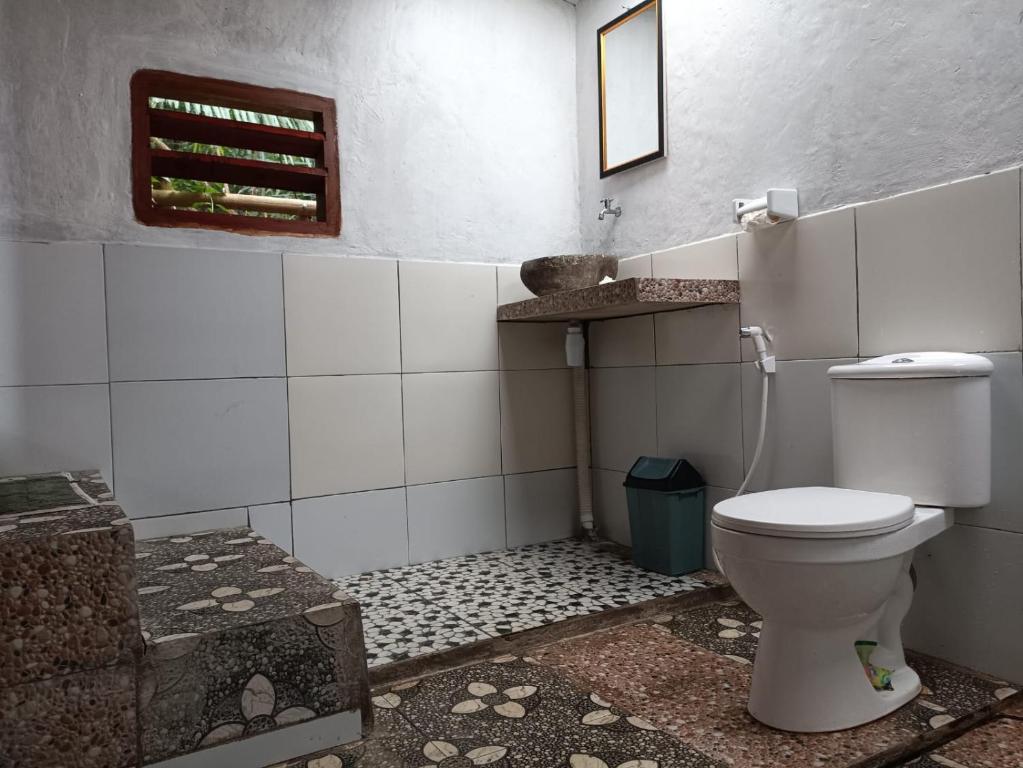 een badkamer met een toilet en een tegelvloer bij Bareng Homestay Tetebatu in Tetebatu
