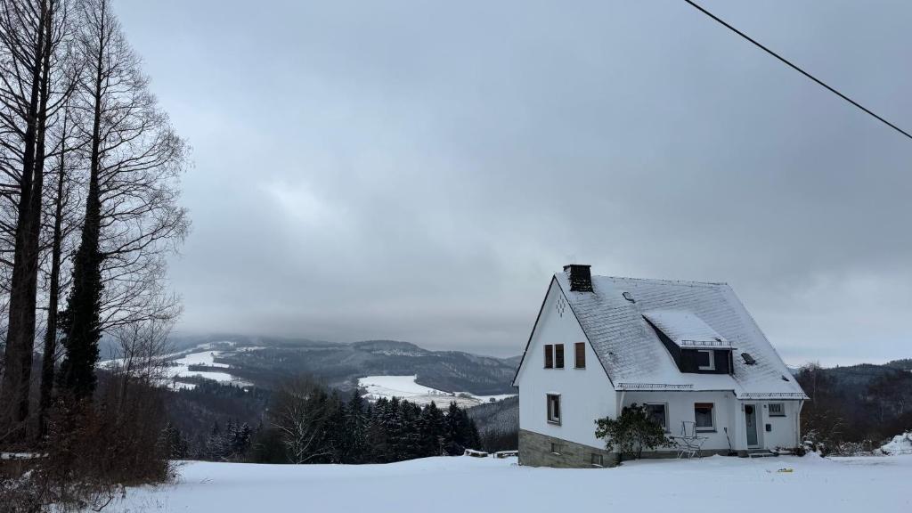 a white house sitting on top of a snow covered hill at Ferienhaus am Vogelsang in Meschede