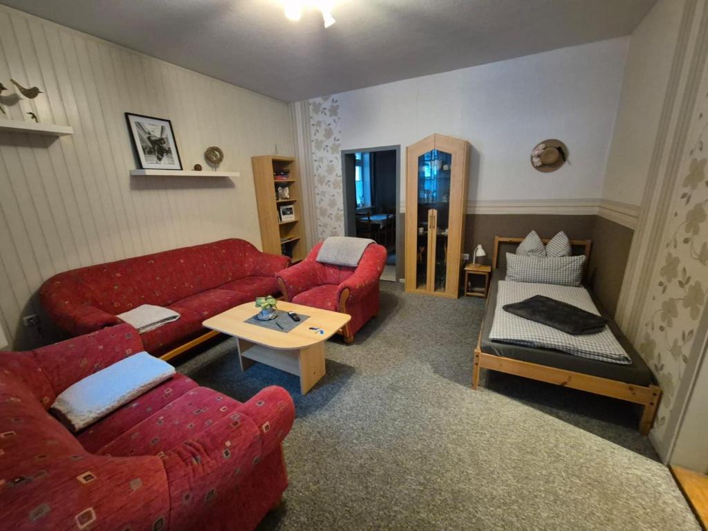 een woonkamer met twee rode banken en een tafel bij Brummers Ferienwohnung in Wildemann