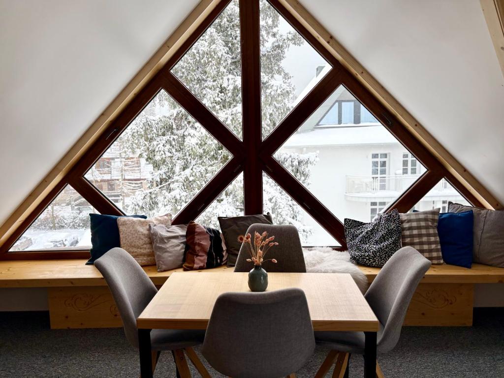 a room with a table and chairs and a large window at Villa Kaplowa Chata & SPA in Zakopane