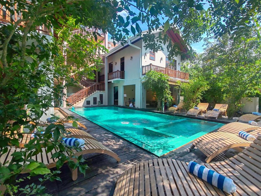 a swimming pool with chairs and a house at Aura By Epic Collection in Mirissa