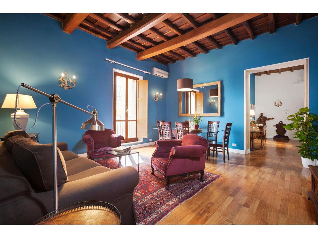 a living room with blue walls and a couch and chairs at Apartment Via Giulia in Rome