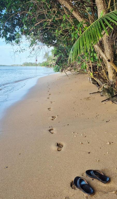 a pair of flip flops on a beach with footprints at Slice of Paradise with Private Beach in Agat