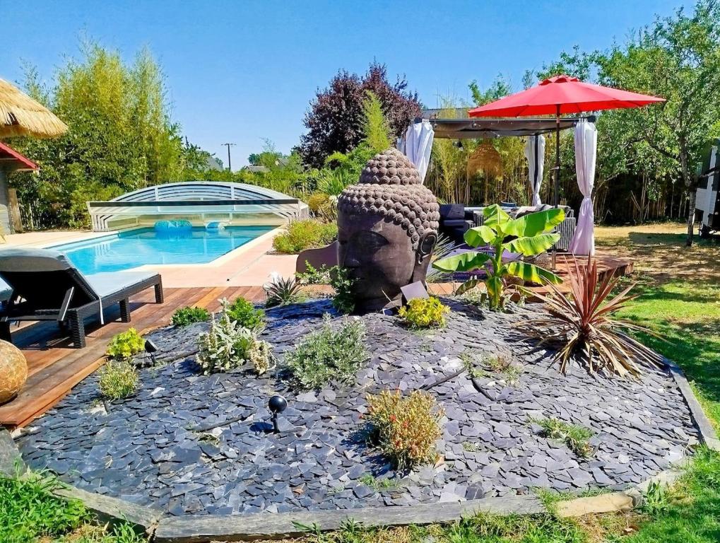 a garden with a statue next to a swimming pool at Petite parenthèse au gîte Layon in Les Garennes sur Loire