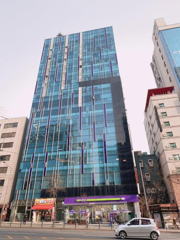 a tall glass building with a car in front of it at Whouse-sinchon in Seoul