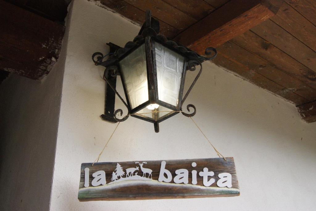 a sign hanging from a ceiling with a light at La Baita Baretana in Barete