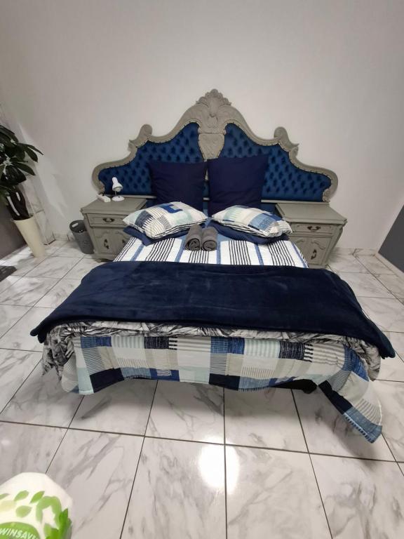 a bedroom with a bed with a blue headboard and pillows at Villa Caramia Guest Lodge in Jan Kempdorp