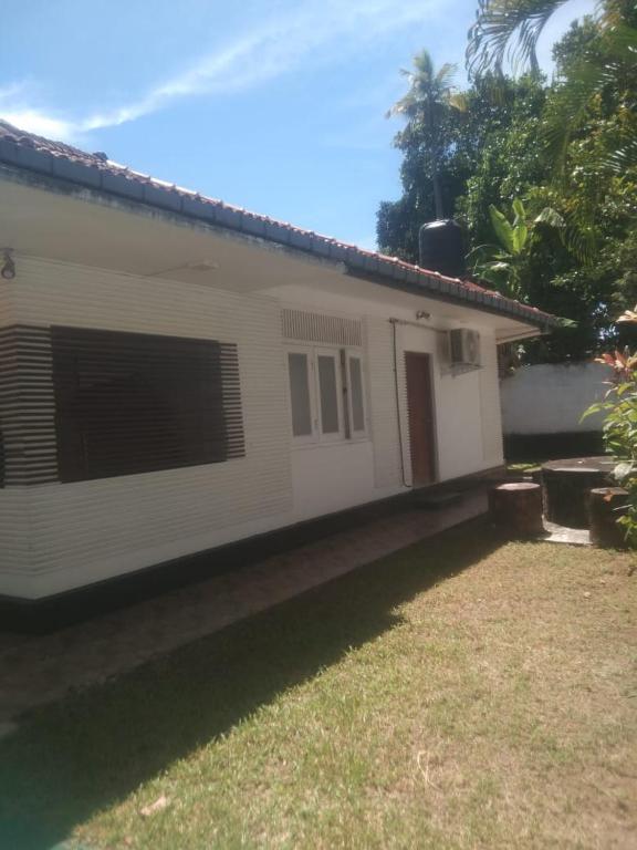 a white house with a yard in front of it at Jayasri in Hikkaduwa