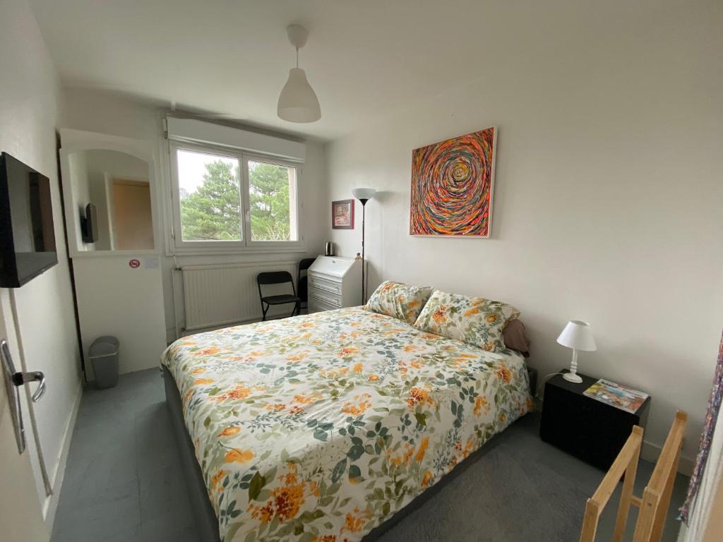 een slaapkamer met een bed met een bloemenbed en een raam bij Bed and Breakfast Nantes au calme proche aéroport, gare et centre-ville in Saint-Sébastien-sur-Loire