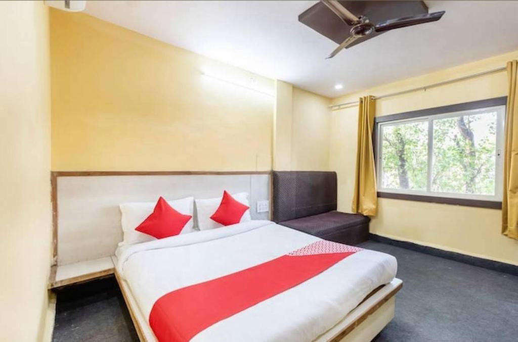a bedroom with a bed with red pillows and a window at Hotel Vanice Blue in Indore