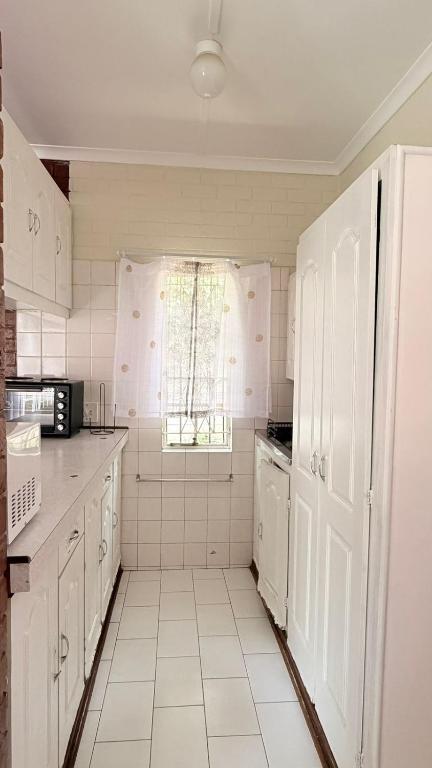 a kitchen with white cabinets and a window at Gaxela Space in Pietermaritzburg