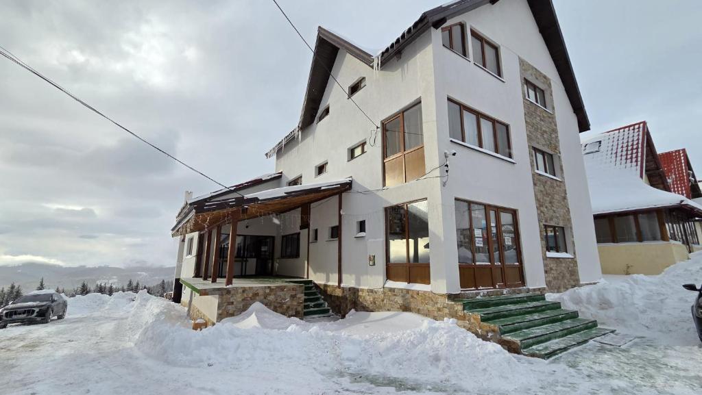 a house is covered in snow at Pensiunea Paradis in Ranca
